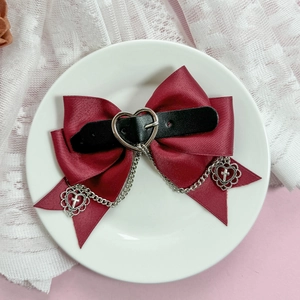Détail du nœud gothique bordeaux avec boucle cœur et pendentif croix sur chaîne