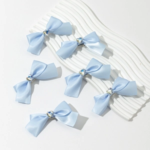 Détail de 6 barrettes à nœuds en satin bleu clair avec centres en strass en forme de cœur