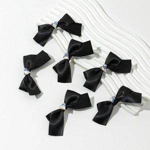 Vue détaillée de six barrettes à nœuds en satin noir avec un cœur en cristal étincelant