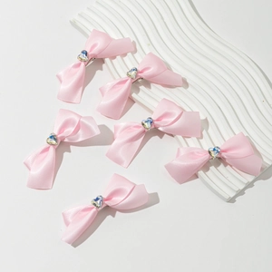 Set de 6 barrettes nœuds en satin rose avec cristal cœur sur un plateau à vagues blanc