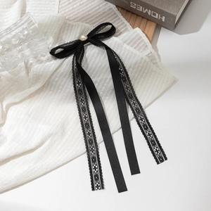 Detailed close-up of a black lace ribbon bow hair clip with central pearl decoration