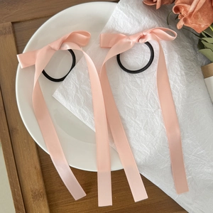 Dettaglio dei fiocchi per capelli in raso rosa con nastri lunghi su un piatto bianco