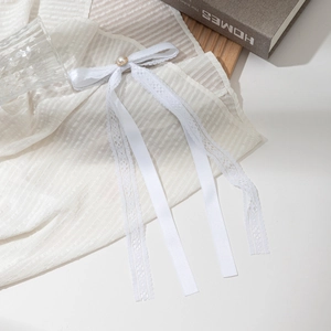 Elegant white lace bow hair clip with pearl detail on aesthetic striped fabric background