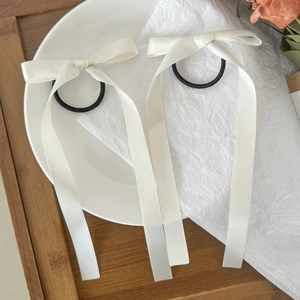 Dettaglio di due elastici per capelli in raso bianco con lunghi nastri eleganti