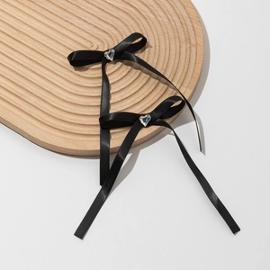 Détail de deux nœuds en satin noir avec strass en forme de cœur sur un plateau en bois