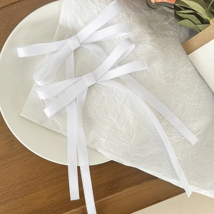 Pair of elegant white satin ribbon bow hair clips with long streamers in minimalist style