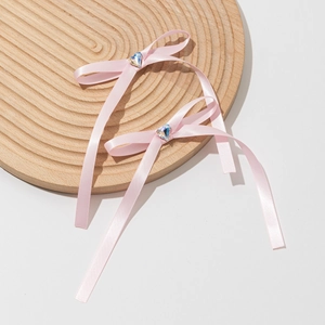 Détail de barrettes nœuds roses avec cristal de cœur sur un plateau en bois rond