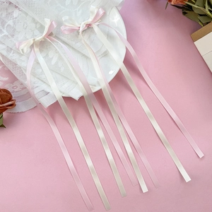 Dettaglio di pizzo floreale bianco con fiocchi in raso rosa cipria e crema delicato