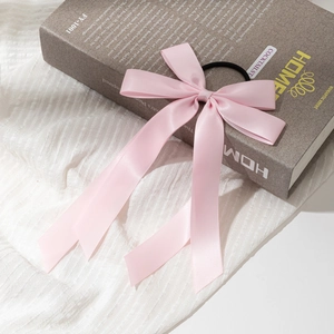 Détail d'un chouchou noeud en satin rose avec éclat soyeux sur support de livre