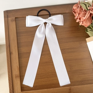 Élastique à cheveux élégant en satin blanc avec rubans longs sur un plateau en bois