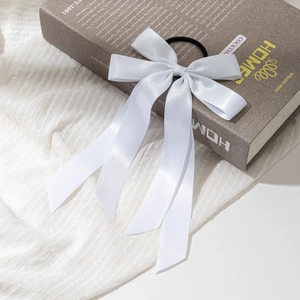 Détail d'un chouchou noeud en satin blanc avec longs rubans sur fond de livre