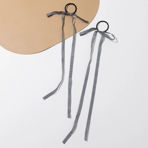 Détail de deux chouchous à nœuds à carreaux noirs et blancs sur un fond de style minimaliste