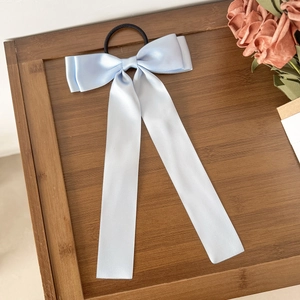 Détail d'un chouchou en satin bleu clair avec ruban élégant sur fond de plateau en bois