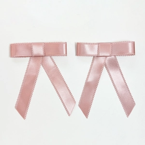 Détail des barrettes nœuds en satin rose avec bords en dentelle et texture de soie douce
