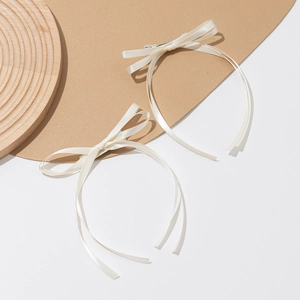 Detail showing a pair of cream satin ribbon bow hair clips with long streamers