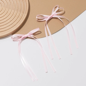 Detail of two pink silk satin bow hair clips with long ribbons on a wooden display
