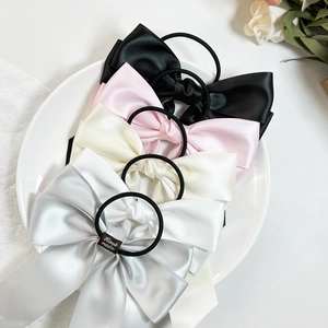 Elegantes Satin-Haargummi-Set in vier Farben auf weißem Porzellanteller präsentiert