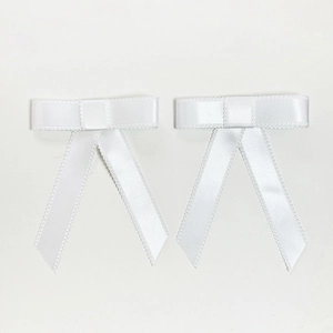 Gros plan d'une paire de nœuds à cheveux en satin blanc avec bordure en dentelle délicate