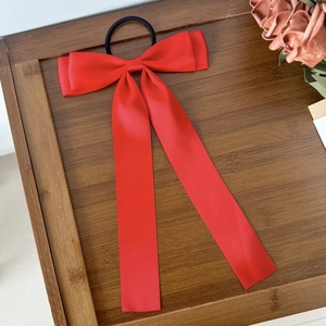 Vue détaillée d'un chouchou en satin rouge avec long ruban sur un plateau en bois