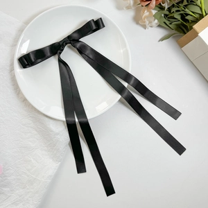 Dettaglio di un fermaglio per capelli a doppio fiocco in raso nero con nastri lunghi eleganti
