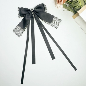 Detail of black satin bow hair clip with lace trim, heart rhinestone and long ribbons