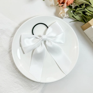 Detail eines eleganten weißen Satin-Haargummis mit Schleife und langen Bändern