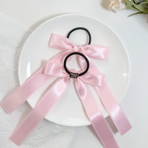 Close-up of pink satin bow hair ties with lace edges and Hand Made fabric label