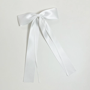 Elegant white satin bow hair clip with long flowing ribbons in a minimalist style