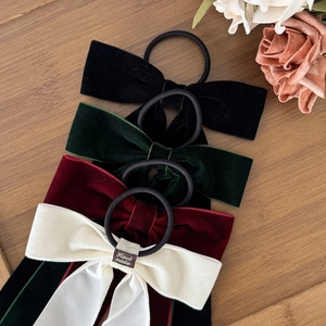 Elegant four-color velvet bow hair scrunchie set with handmade label on wooden background