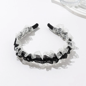 Detail of elegant black and white lace headband with floral embroidery and pleats