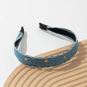 Detailed view of light blue denim headband with gold star embroidery and white stitching