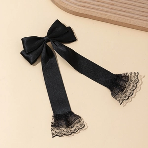 Detail of black satin bow hair clip with long ribbons and delicate lace trim edges