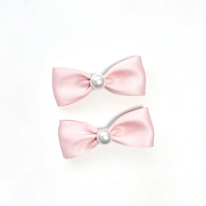 Set di due fermagli per capelli con fiocco in raso rosa e perla su sfondo bianco