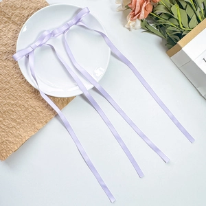 Detail of light purple satin bow hair clips with long elegant ribbon streamers on a tray