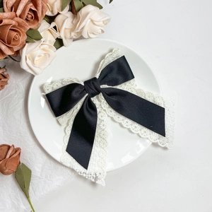 Detail of elegant black satin and white lace layered bow hairpin with flowing ribbons