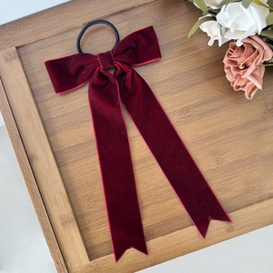 Macro detail of the deep red velvet bow hair scrunchie with long trailing ribbons
