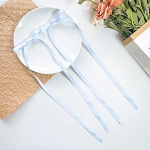 Detail view of two light blue satin ribbon bows placed on a white ceramic plate