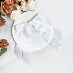 Elegant white double-layered satin bow hair clip with long ribbons on white plate