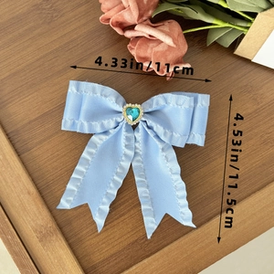 Detail view of a light blue bow hair clip with a heart gemstone and size dimensions