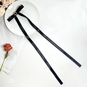 Close-up of black ribbon bow hair clip with rhinestone heart center on white plate
