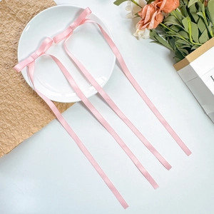 Close-up of pink satin ribbon bow hair clips with long streamers on a white decorative plate