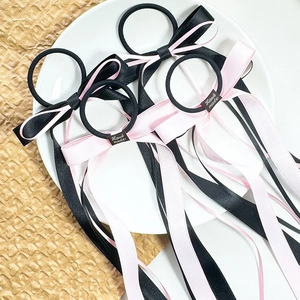 Elastici per capelli con fiocchi rosa e neri e lunghi nastri su un piatto decorativo