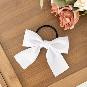 Elegant white bow hair tie with high elasticity black band on aesthetic wooden tray