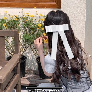 Pince à cheveux élégante avec grand nœud en satin blanc et rubans sur cheveux bouclés