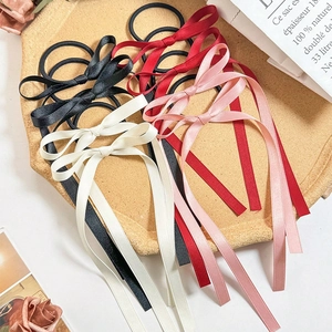Detail of satin bow hair ties in black, burgundy, pink, and cream on a wooden tray