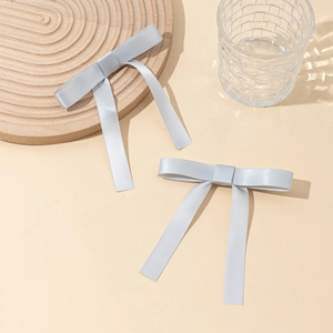 Détail de pinces à cheveux nœuds en satin gris clair avec de longs rubans fluides