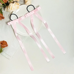 Zweier-Set rosa Satin-Haargummis mit langen Schleifen auf einem weißen Keramikteller