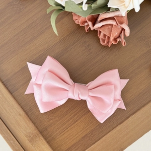 Elegant pink satin double-layered bow hair clip with a vintage aesthetic on wooden surface
