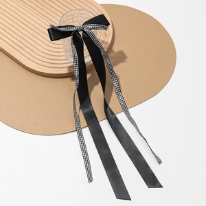Détail d'un nœud papillon en satin noir et ruban à carreaux avec de longs pompons