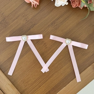 Barrettes à cheveux nœud rose avec perle de cœur sur fond en bois rustique